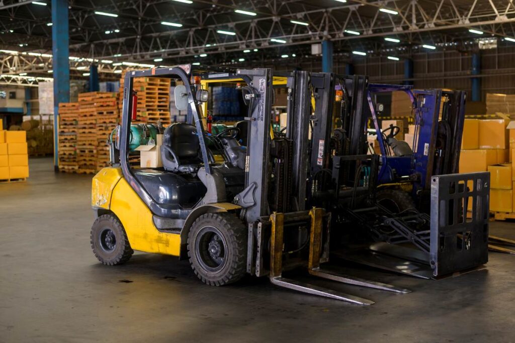 Forklift loader in warehouse with pallets and boxes in the background