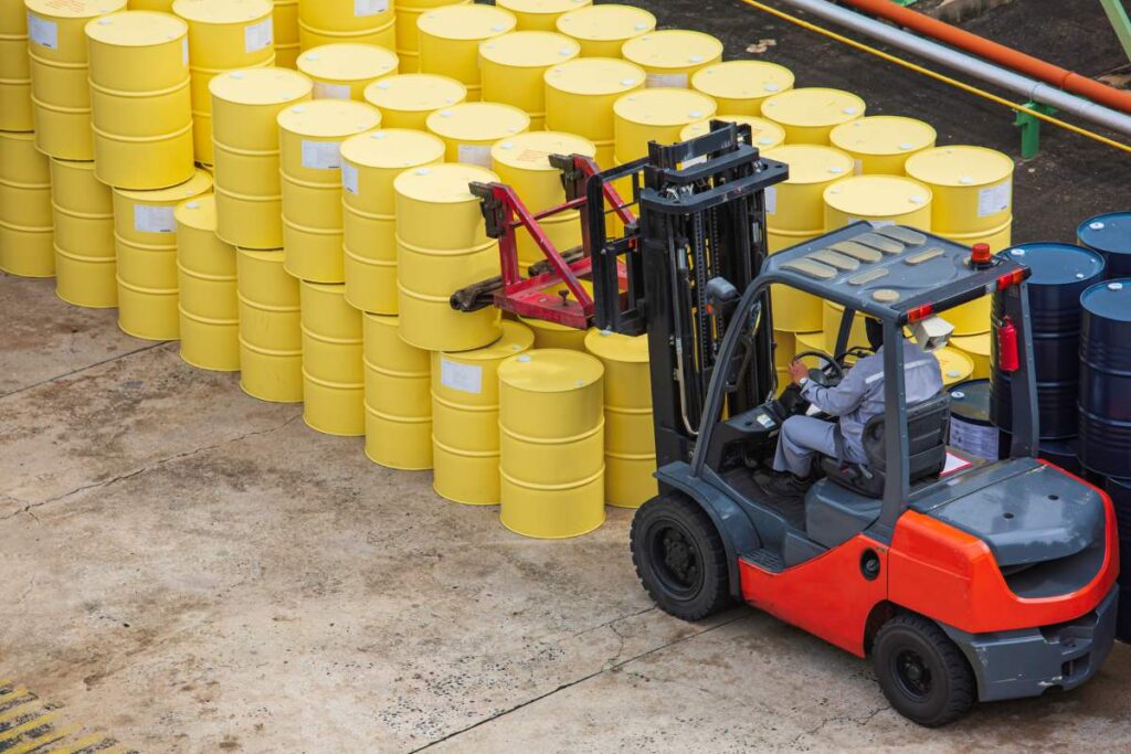 top view of forklift transporting yellow oil barrels 