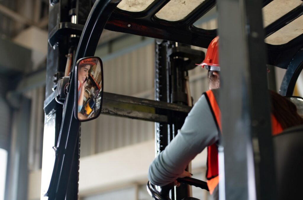 woman wearing a red safety hat operating a forklift