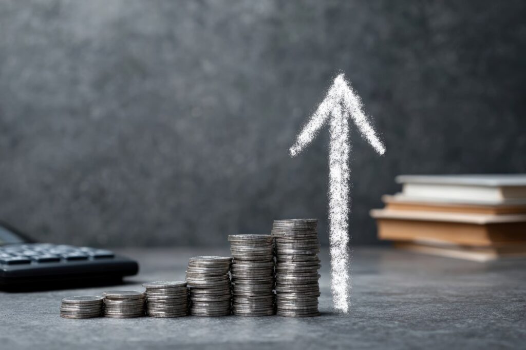 stack of coins with white arrow pointing up depicting increased or higher cost 