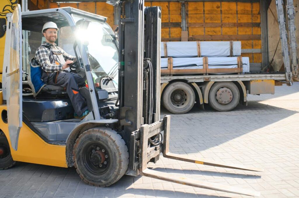 A man on a forklift works in a large warehouse