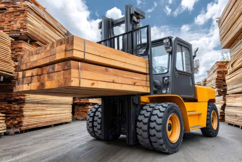Forklift transporting lumber planks in timber warehouse