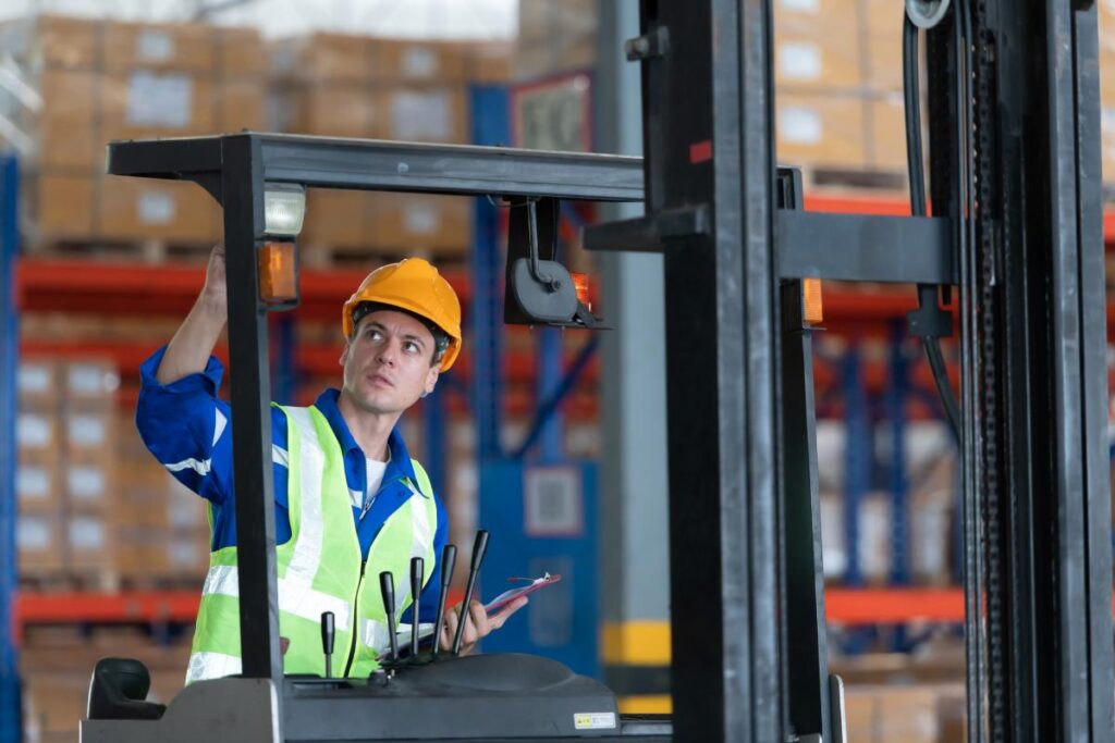 Worker in auto parts warehouse use a forklift to work to bring the box of auto parts into the storage shelf of the warehouse waiting for delivery to the car assembly line