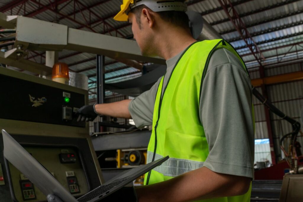 Industrial worker operating machinery factory professional service indoor environment side view safety protocols