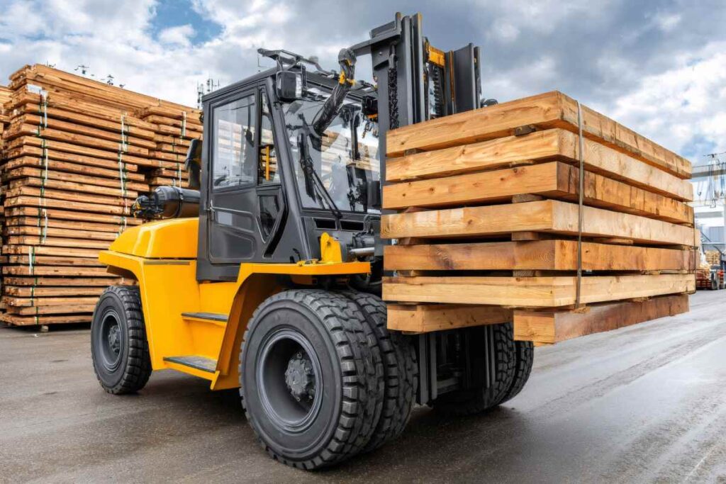 Yellow forklift transporting wooden planks at industrial outdoor storage