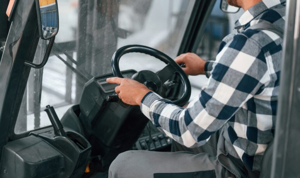 In forklift.. Factory male worker in uniform is indoors