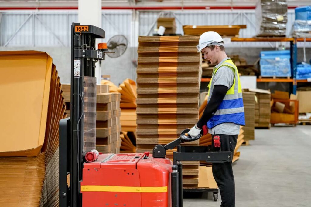 A man is standing next to a forklift in a warehouse