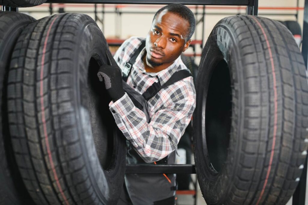 Portrait, of happy african male auto mechanic in the background of a tires service canter concept